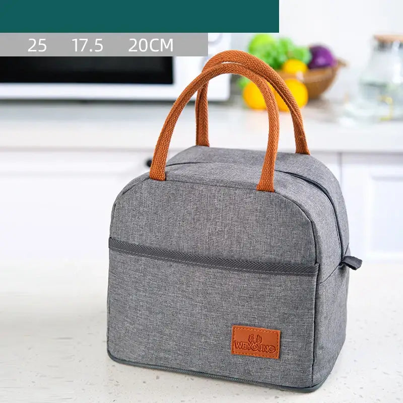 Gray textured insulated lunch bag with orange rope handles and brown leather brand patch for kitchen thermal use