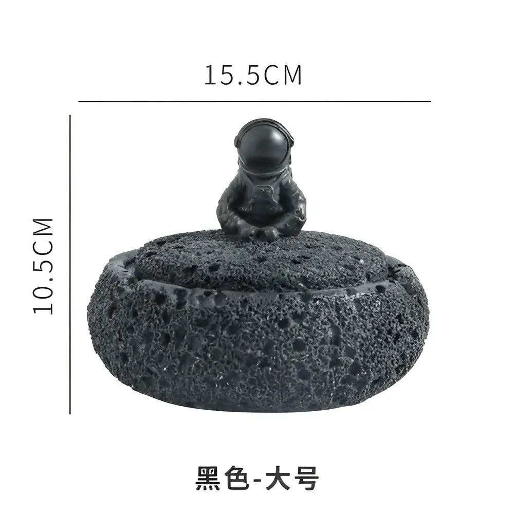 Gray volcanic stone cement astronaut ashtray with a glossy black helmeted figure and textured porous base for living room use