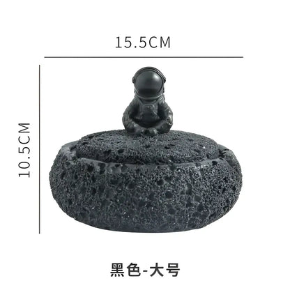 Gray volcanic stone cement astronaut ashtray with a glossy black helmeted figure and textured porous base for living room use