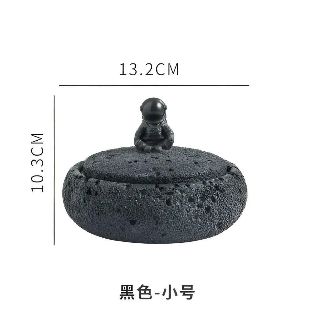 Black textured ceramic cement astronaut ashtray with a miniature astronaut figurine on its domed lid for living room use
