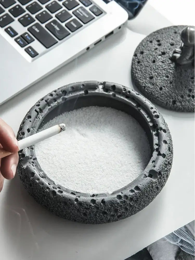 Gray volcanic stone cement astronaut ashtray with porous lava rock texture and astronaut figurine lid for living room use