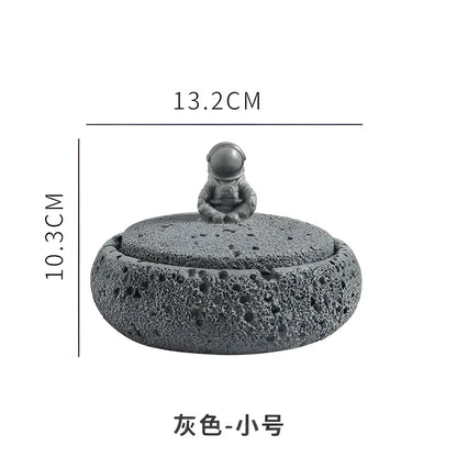 Gray volcanic stone cement astronaut ashtray with textured lid and miniature gray astronaut figurine for living room use