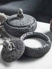 Gray volcanic stone ashtray featuring a miniature cement astronaut figurine for living room use as an astronaut ashtray