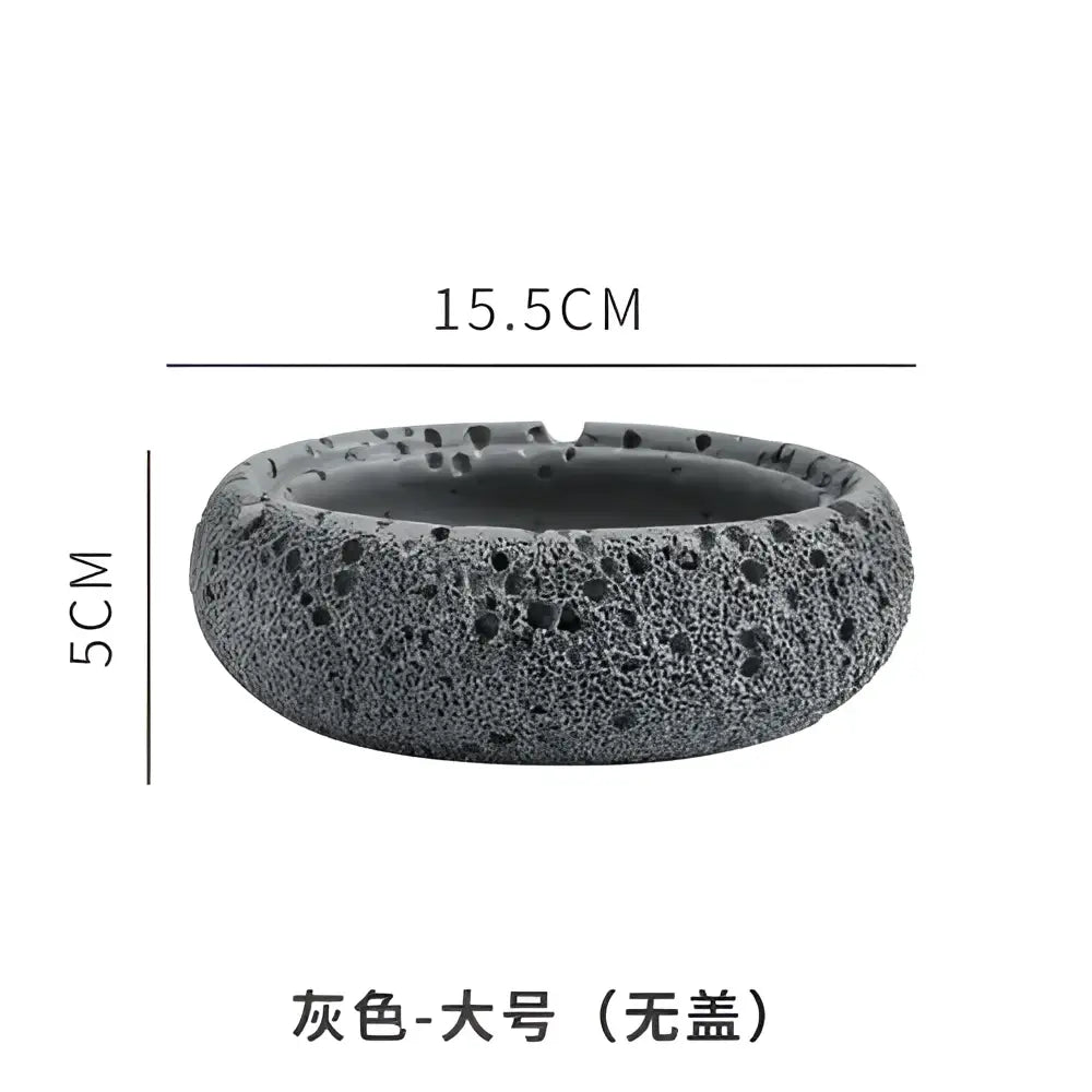 Gray volcanic stone cement astronaut ashtray with textured porous surface and rounded edges for living room use