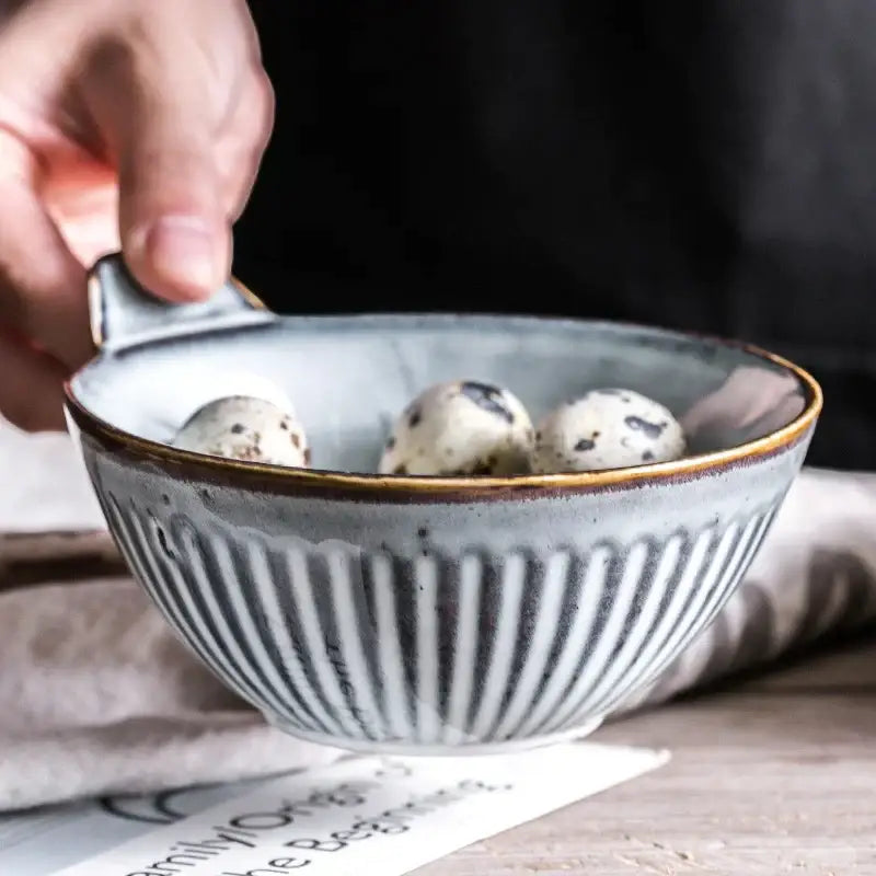 A rustic gray ceramic bowl with vertical ridges and gold rim from a ceramic wedding tableware set by decorbites