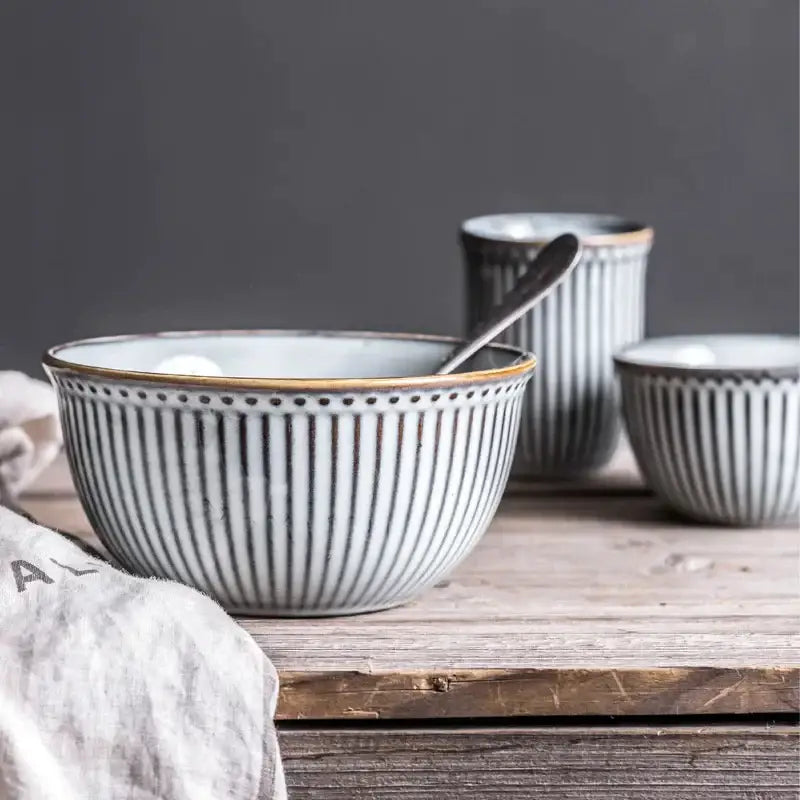 White ceramic bowl with vertical black stripes and gold rim from gray and white striped ceramic wedding tableware set