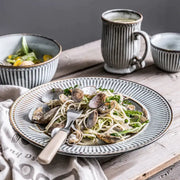 A gray and white striped ceramic wedding tableware set plate with textured rim serving clams over pasta by decorbites ceramic wedding