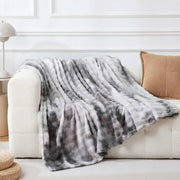 Gray and white tie-dye fuzzy faux fur blanket draped over cream sofa featuring soft decorbites fuzzy faux texture