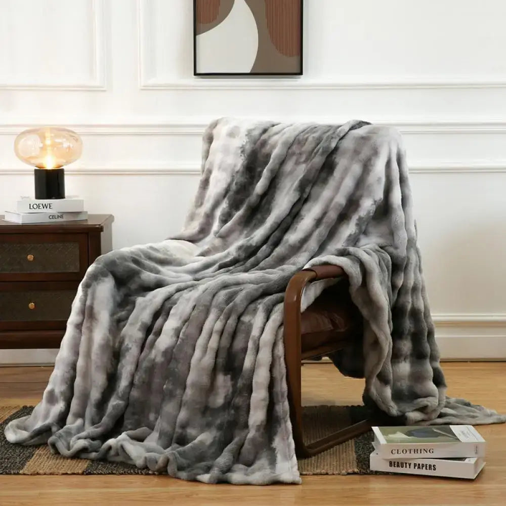 A gray and white tie-dye fuzzy faux fur blanket draped over a wooden chair showcasing decorbites fuzzy faux fur texture