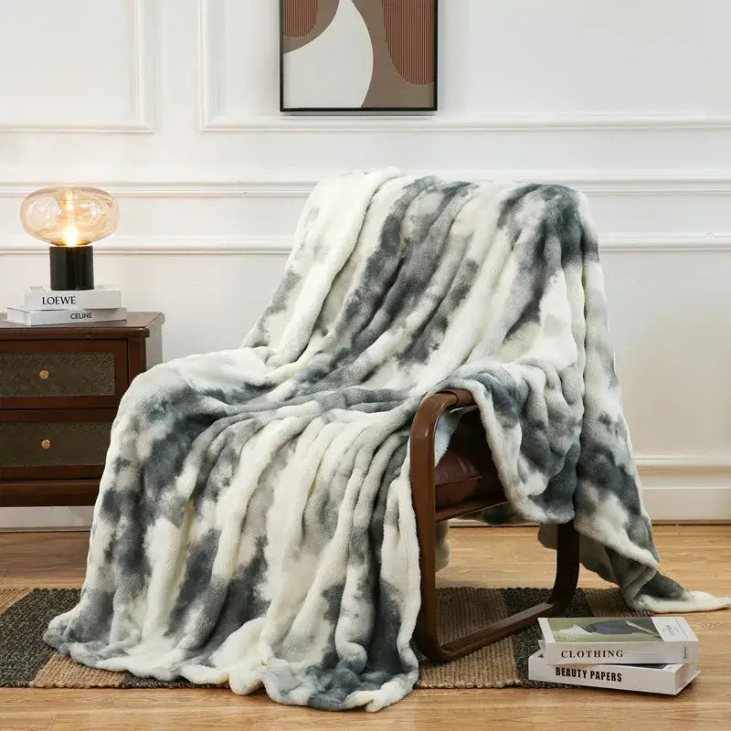 A gray and white tie-dye fuzzy faux fur blanket draped over an armchair enhancing cozy decorbites fuzzy faux decor