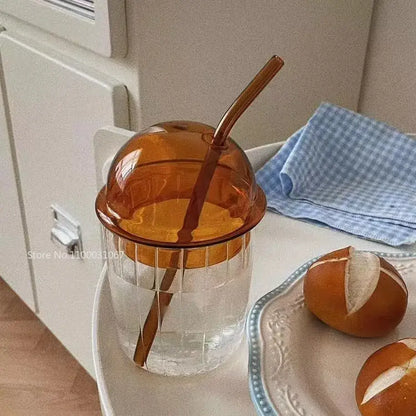 A clear glass cup with a ribbed texture and amber dome lid with matching straw decorbites 450ml striped glass