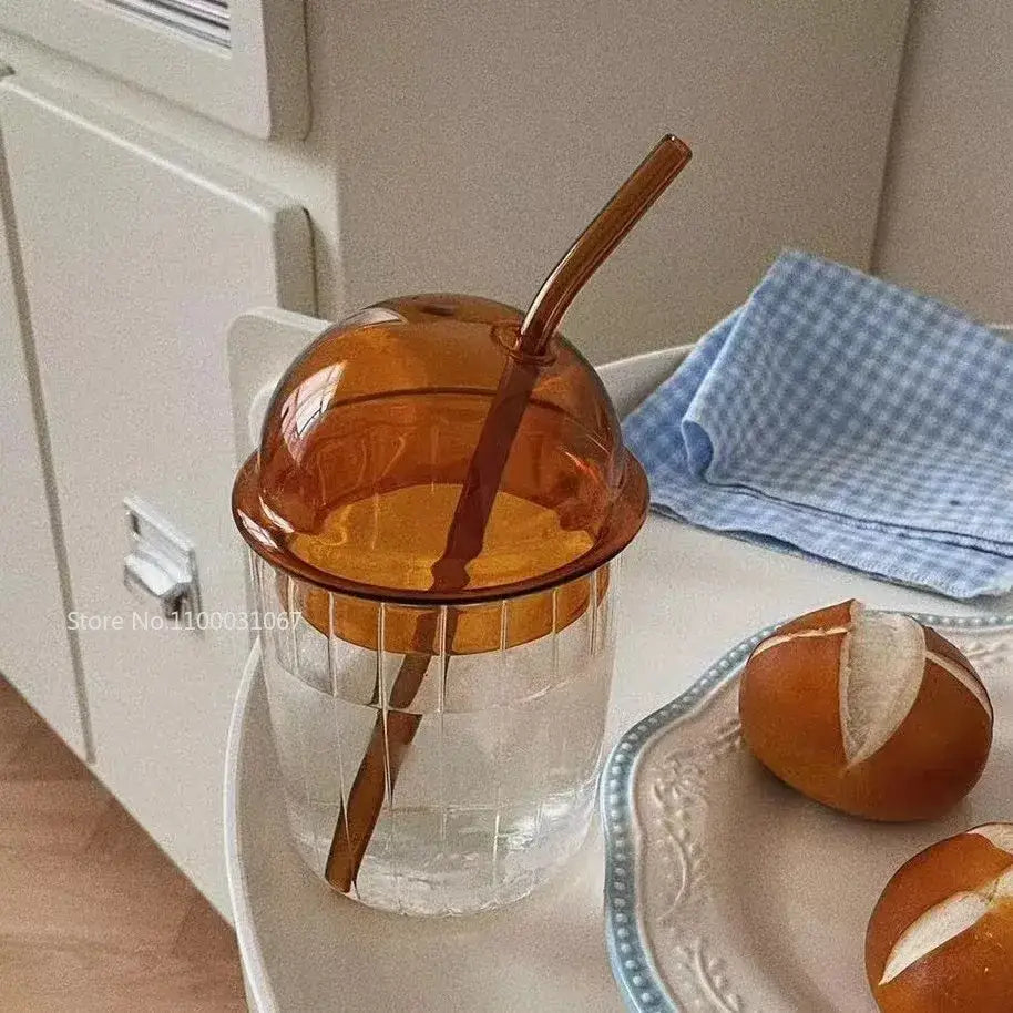 A clear glass cup with a ribbed texture and amber dome lid with matching straw decorbites 450ml striped glass