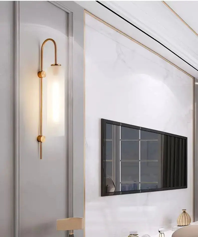 Gold-toned wall sconce with curved minimalist design and frosted glass diffuser complementing green glass nordic pendant light