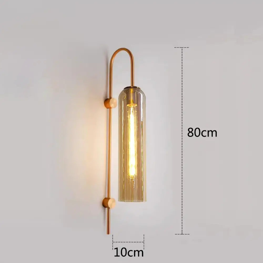 A modern brass wall sconce with amber glass and exposed filament bulb paired with green glass nordic pendant light