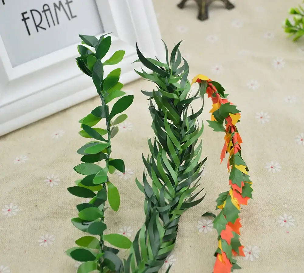 Three artificial leaf vine wreath garlands with green rounded leaves, pointed leaves, and autumn-colored paper leaves for decor