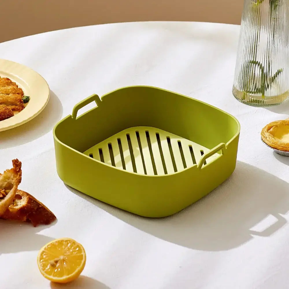 A lime green silicone air fryer baking tray with slatted bottom and side handles for kitchen use