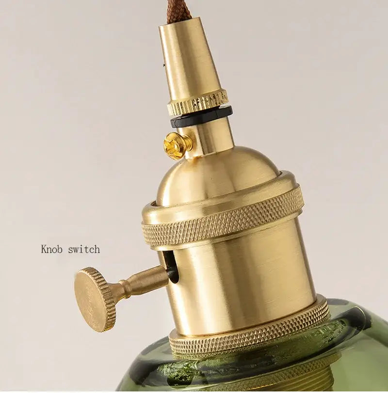 Brass knob switch with textured ridged bands and golden finish on green and clear glass pendant light decorbites copper base