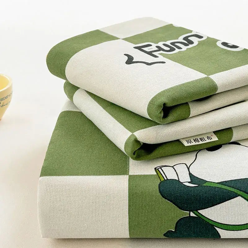 Folded green and white checkered decorbites cartoon printed cotton bedspread with a panda holding a book design