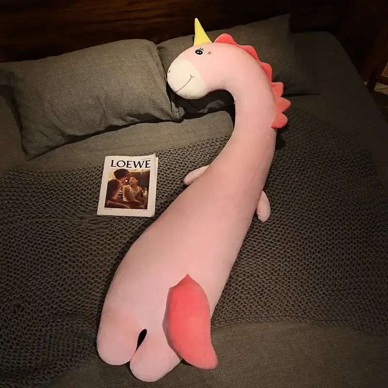 A soft pink plush unicorn with a yellow horn and red mane as a decorbites cartoon animal body pillow for bedroom decor