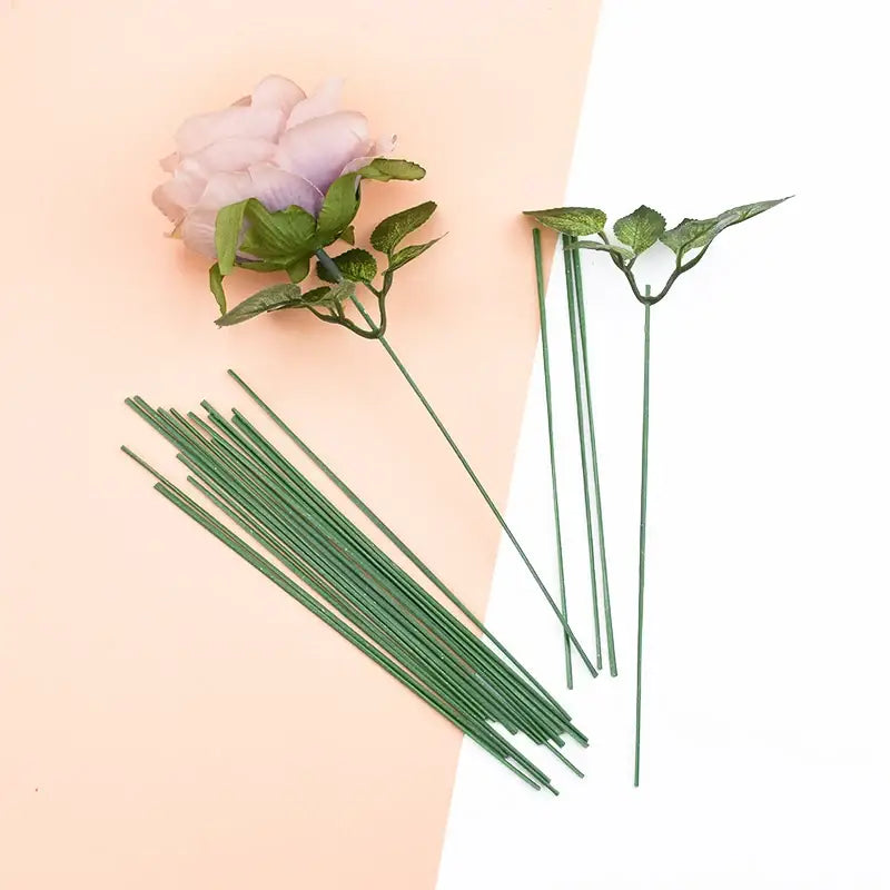 A delicate pink artificial flower with green leaves and iron wire rose stems ideal for decorbites wedding decor