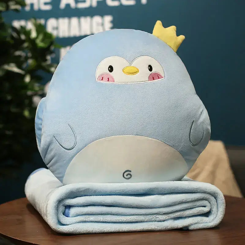 Light blue plush penguin cartoon animal throw with yellow crown sitting on matching pillow blanket decorbites decor