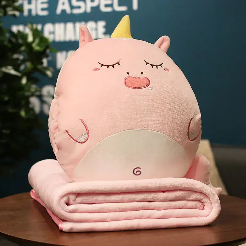 Pink plush unicorn pillow blanket with yellow horn and embroidered face resting on pink fleece decorbites cartoon animal throw