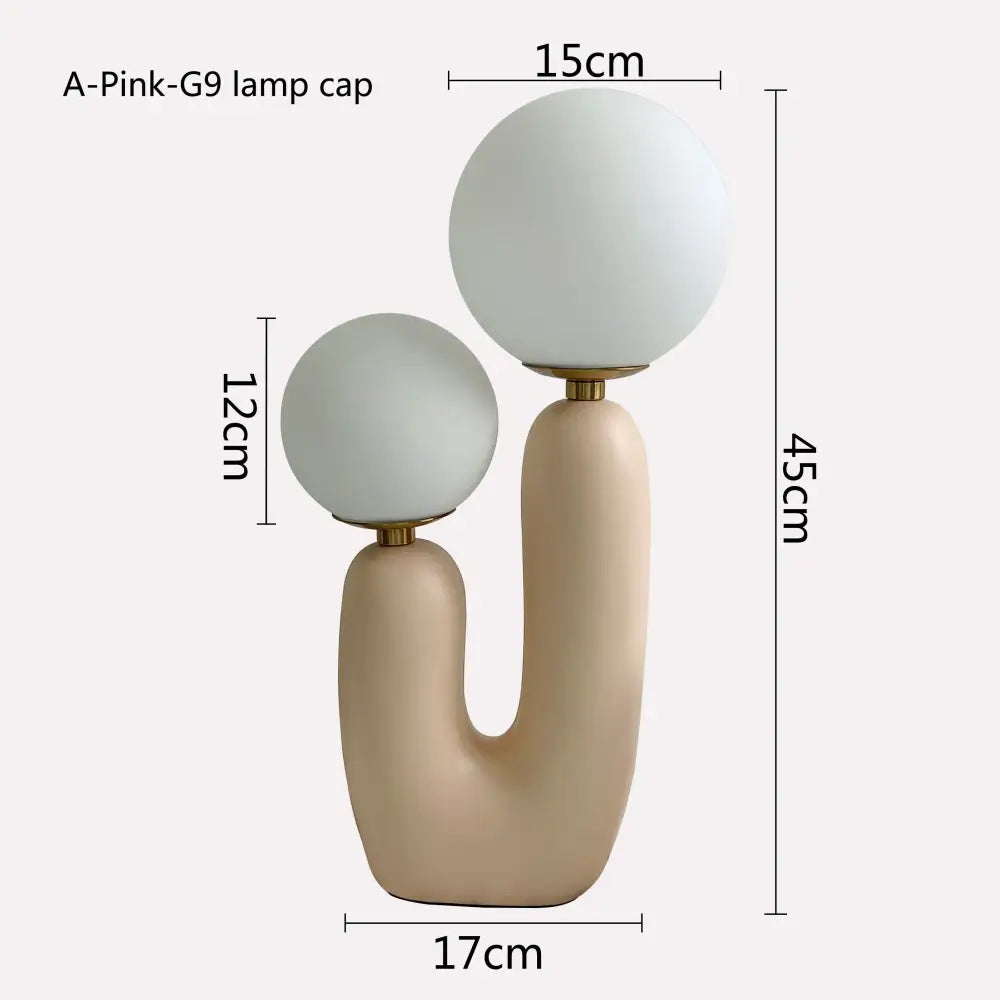 Cream-colored ceramic table lamp with double frosted glass globe shades and gold-toned metal fittings for bedroom use