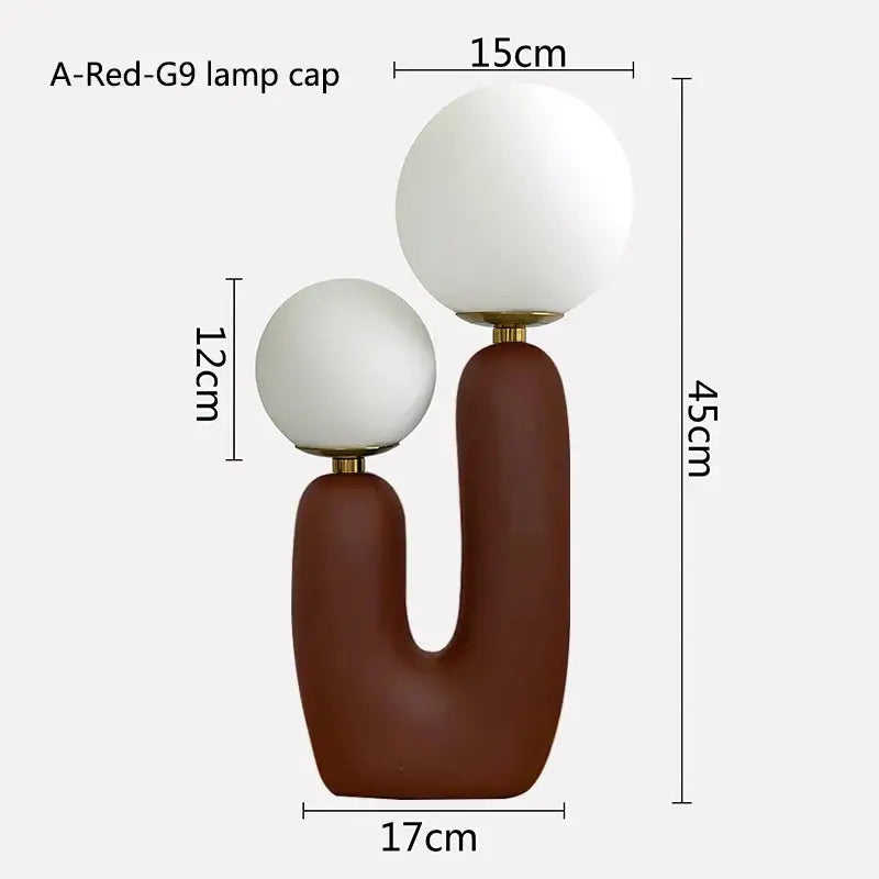 A modern table lamp with a matte brown ceramic base and double frosted glass white spherical shades for bedroom use