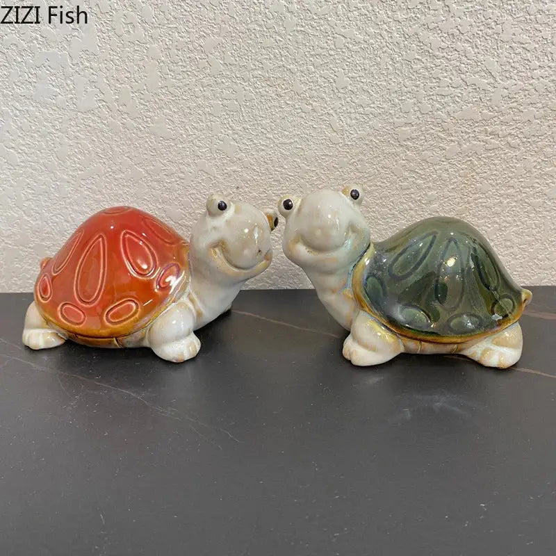 Two ceramic turtle statues with glossy orange and greenish blue shells as desk decoration trinket dishes