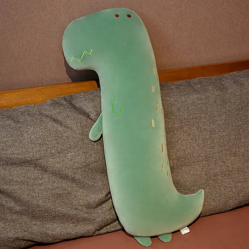 A soft mint green plush green dinosaur cartoon comfort body pillow with embroidered details and orange eye patches