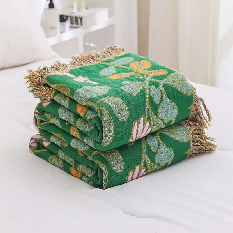 Folded green decorbites cotton tassel sofa blanket with embroidered floral patterns and fringed edges for living room decor