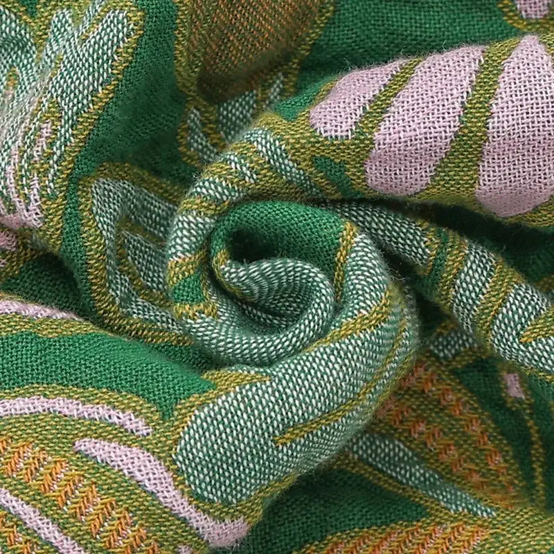 A decorbites cotton tassel sofa blanket in green featuring vibrant pink and gold leaf motifs for living room decor