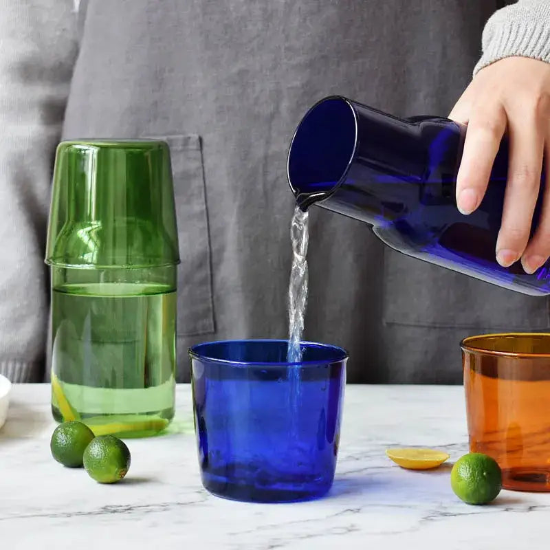 Deep blue glass 550ml bedside water carafe with sleek modern design being poured into matching bedside water glass