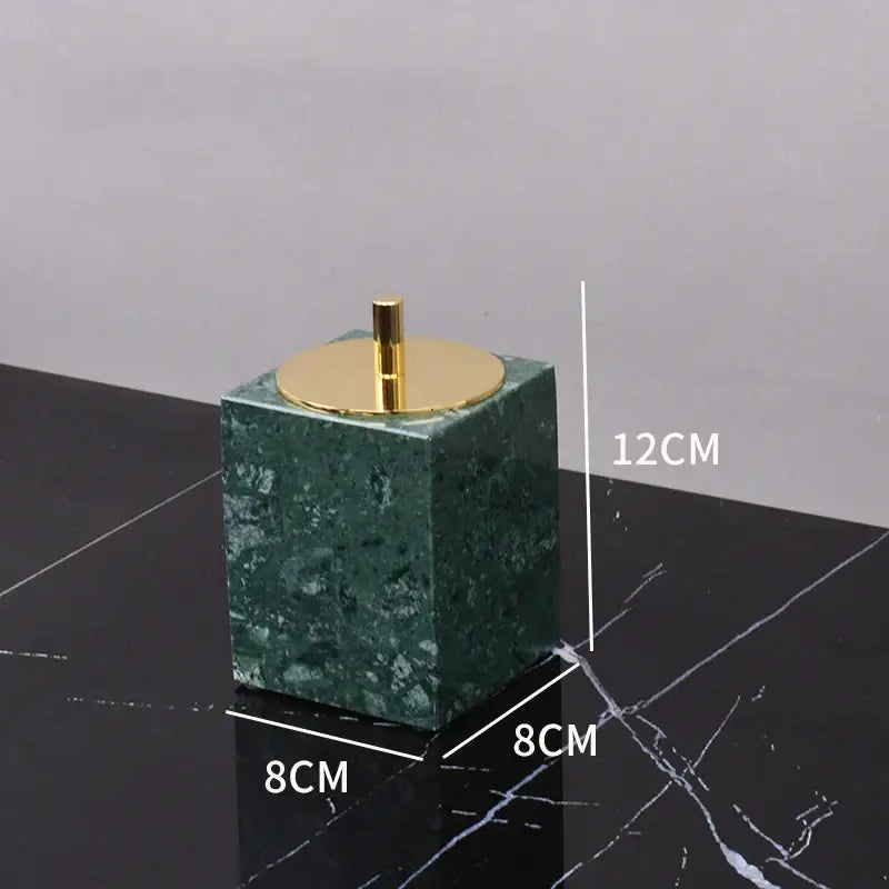 Green marble cube-shaped toothbrush holder with gold-toned lid and stem from marble bathroom set with gold accents