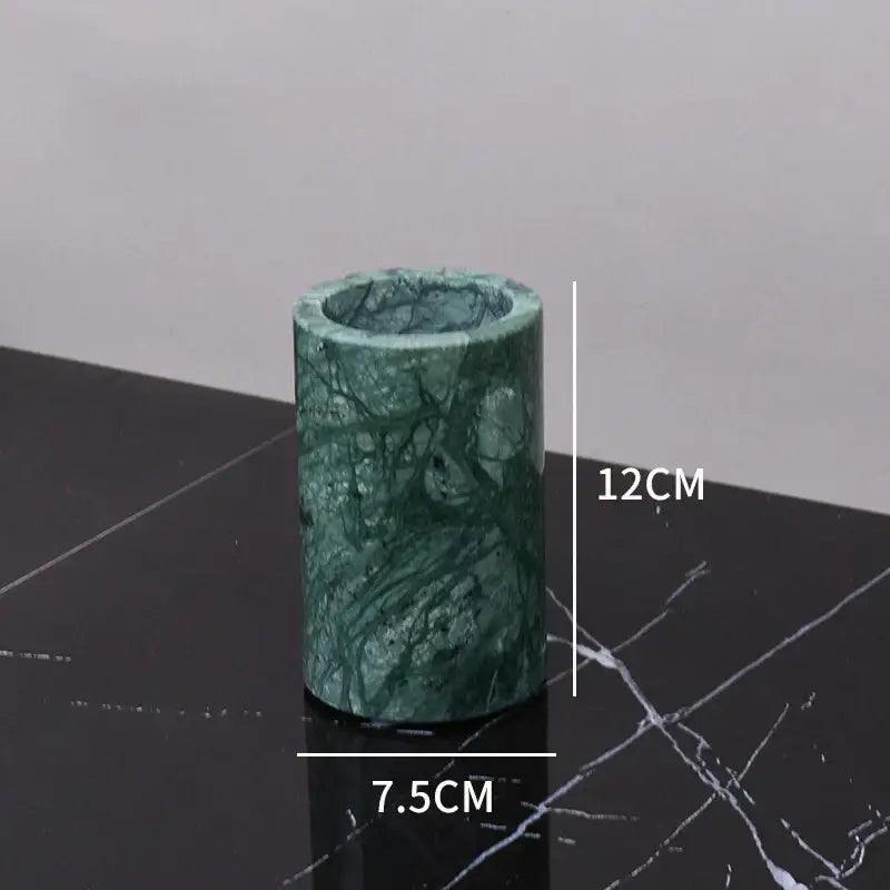 A cylindrical green marble candle holder with polished surface and natural veining from a green marble bathroom set