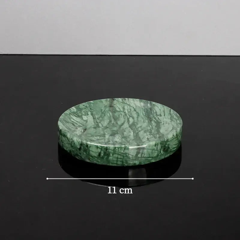A polished green marble soap dish with smooth rounded surface and natural veining from a green marble bathroom set