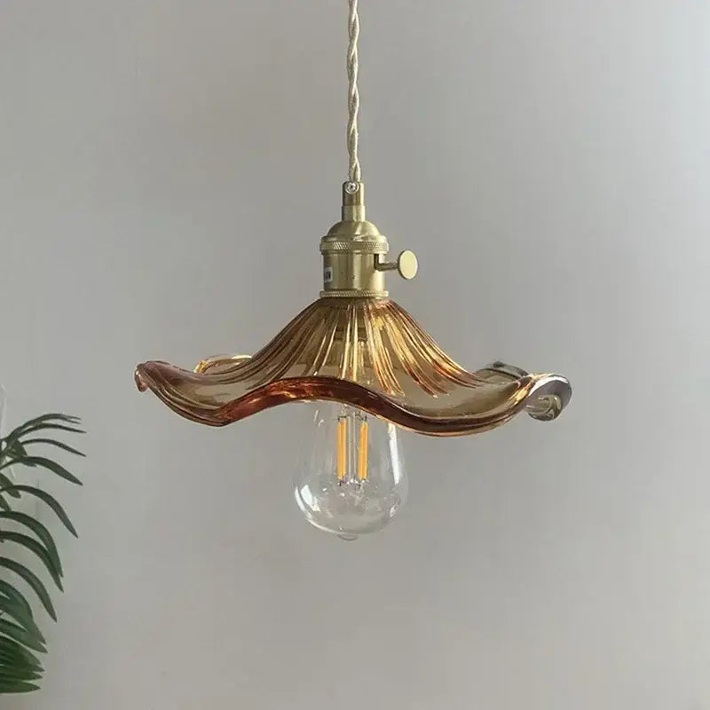 A delicate amber glass pendant light with fluted design and polished copper hardware for dining room use