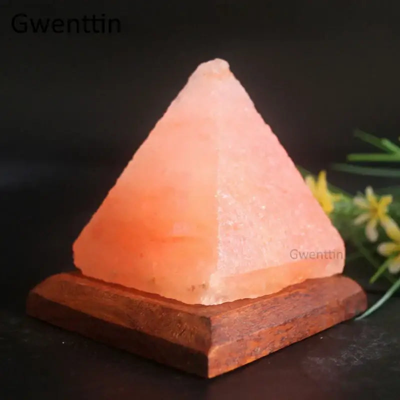 A pink himalayan salt pyramid lamp with warm glowing light on a rustic wooden base decorbites crystal usb salt night light