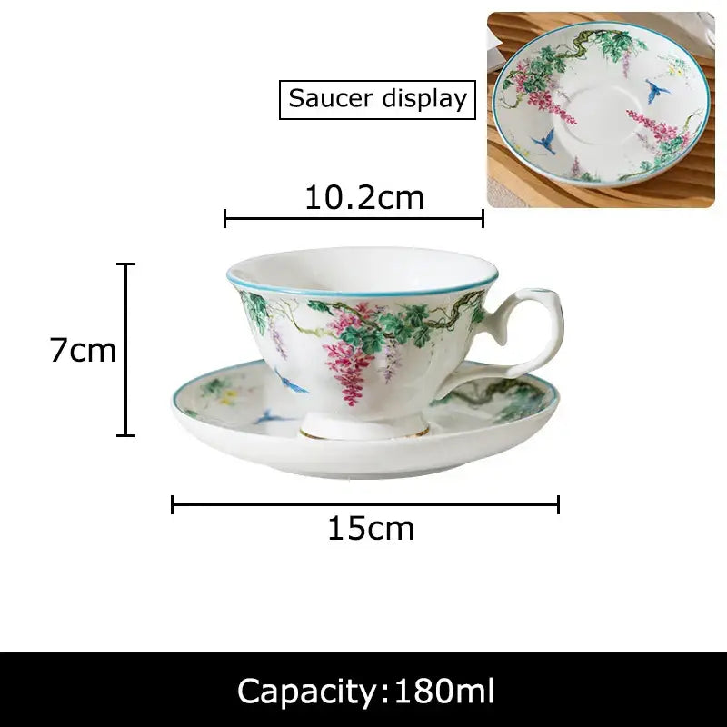 A delicate white green willow porcelain tea cup with pink floral and bird design and a thin turquoise rim