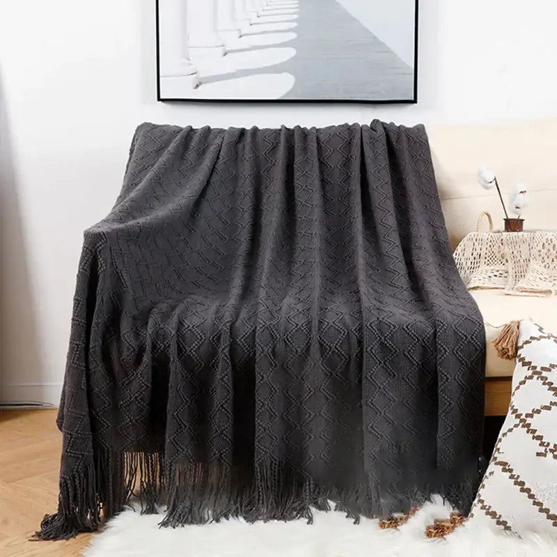Dark gray knitted throw blanket with diamond pattern and fringe featuring decorbites grey nordic waffle knit texture