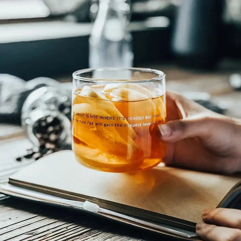 A clear glass coffee cup from decorbites glass coffee cup set filled with amber liquid and black printed quote decor
