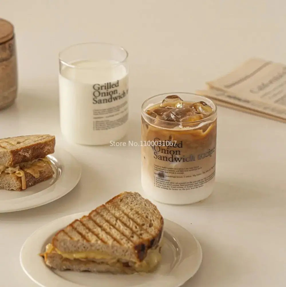 A clear glass coffee cup filled with iced coffee and ice cubes labeled grilled onion sandwich for decorbites glass coffee set