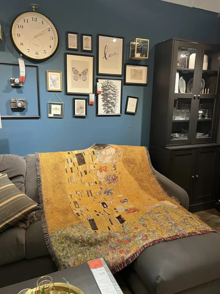 Golden-yellow woven bedroom blanket featuring gustav klimt the kiss art pattern draped over a gray sofa decorbites gustav klimt