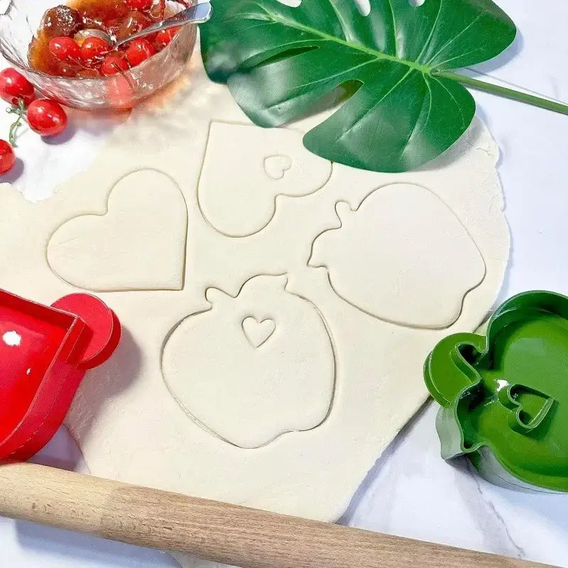 Red plastic heart-shaped hand pie mold with handle beside a green mold in a halloween hand pie molds set