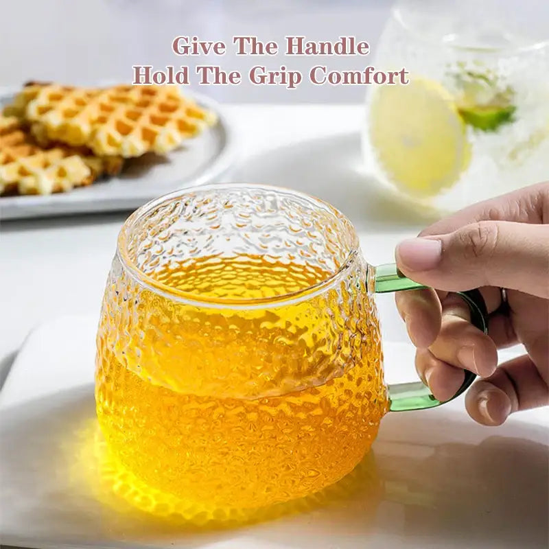 Clear textured 400ml hammer pattern glass mug with green handle filled with golden liquid kitchen glassware