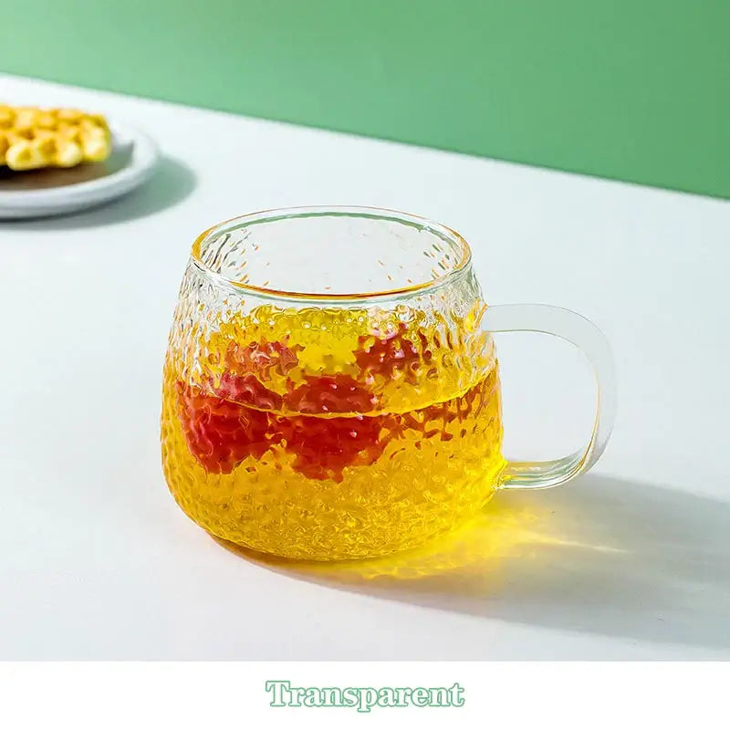 Clear textured 400ml hammer pattern glass mug with colorful handle filled with layered yellow and red liquid