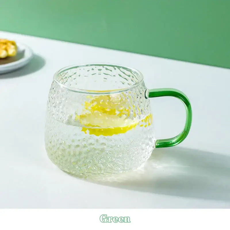 Clear 400ml hammer pattern glass mug with vibrant green handle filled with water and lemon slice for kitchen use