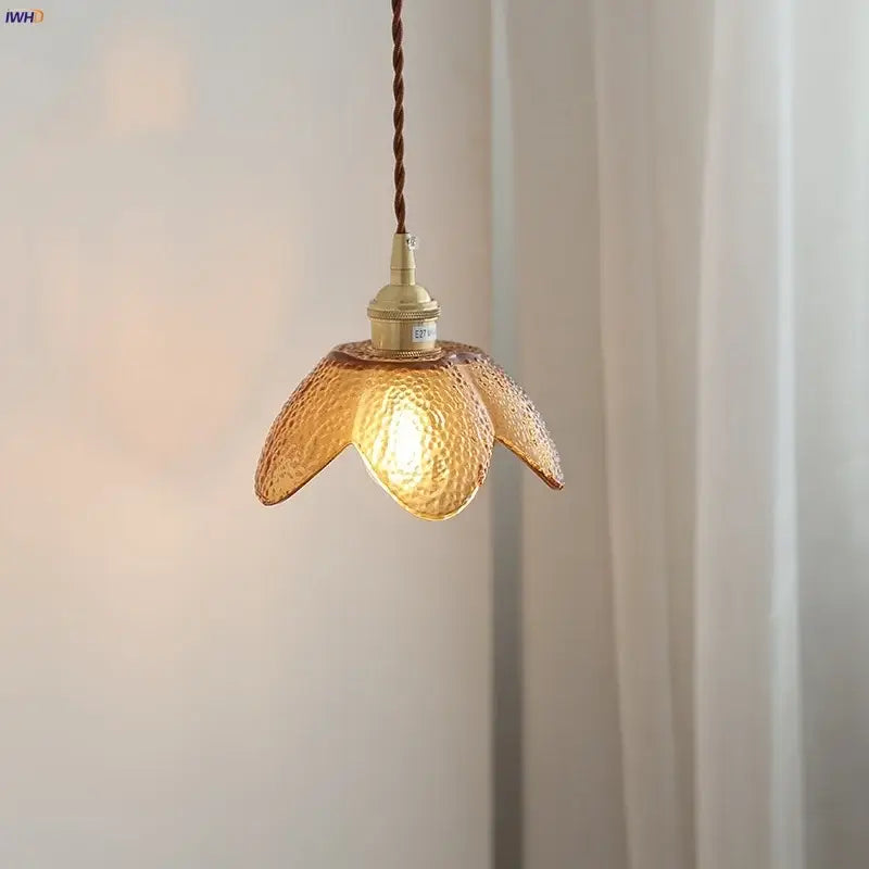 A warm amber glass led pendant light with hammered texture, brass socket, and twisted brown cord for kitchen use