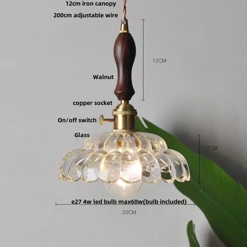 A clear flower-shaped amber glass led pendant light with a dark walnut wooden handle and brass accents