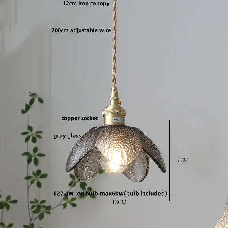 A delicate gray hammered glass led pendant light with petal design hangs from an adjustable copper socket